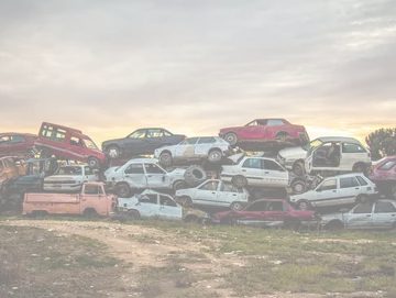 Pile of junk cars waiting to be recycled outside a recycling facility